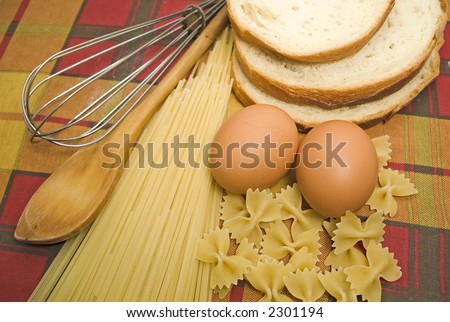 Pasta spaghetti with eggs, bread and kitchen tools over rustic background
