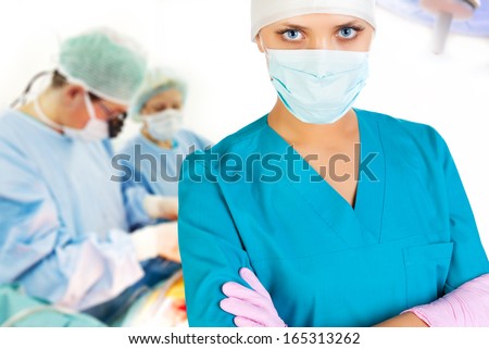 Female surgeon in operation room with working assistents on background