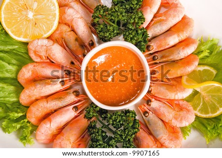 shrimps with lemon, sauce and lettuce on plate
