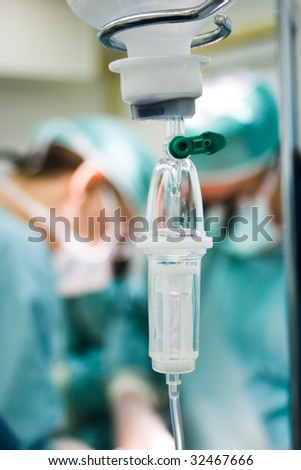 intravenous drip in operation room with surgeons on background