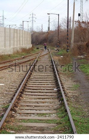 Rail track with a man walking his dog in the background, at an industrial area in Brno, Czech Republic