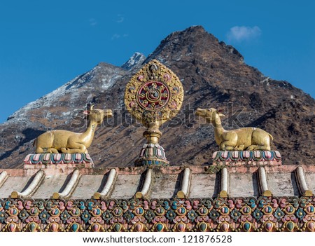 The sculpture of the wheel of Dharma and two deer on the roof of the gate of the monastery Tengboche with mountains on background - Nepal