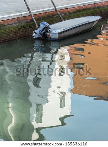 The reflection in the water of the channel of the colored houses - Burano, Venice, Italy