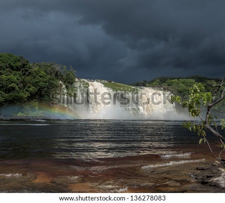 Hacha falls with rainbow  in the lagoon of the Canaima national park before the storm - Venezuela, Latin America