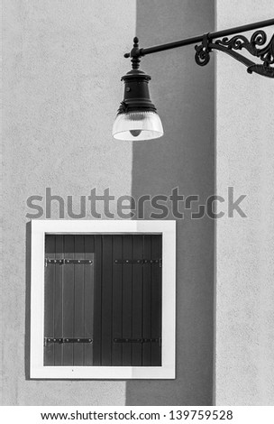An old lantern and the window paint a house on the street of the town - Burano, Venice, Italy (black and white)