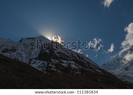 The sun hides behind the Himalayan peaks in the area of ice circus Annapurna Annapurna South - Nepal