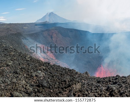Boiling lava and volcanic bombs in a breakthrough on the slopes of the crater of the volcano cone Tolbachic, on background volcano Bolshaya Udina - Kamchatka, Russia
