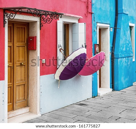 Two multi-colored umbrella hanging on the wall on the island of Burano - Venice, Italy