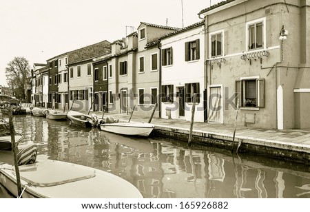 The colored houses on the shore of a narrow channel the Island of Burano - Venice, Italy (stylized retro)