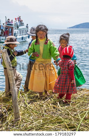 TITICACA, PERU - JAN 03, 2014: Unidentified indian children welcome tourists on island Uros in Lake Titicaca. The Qhichwa Uros are a pre-Incan people who live on 42 self-fashioned floating islands