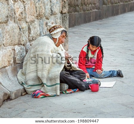 CUSCO, PERU - JANUARY 02, 2014: An old Indian man and a young girl sitting near the walls of the Cathedral of Cusco in Sacred valley of the Incas of Peru