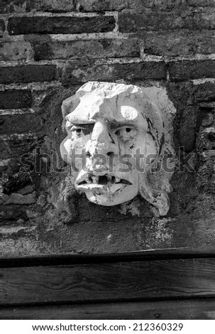 Ancient sculpture of a man\'s head on the wall of a Venetian home - Venice, Italy (black and white)