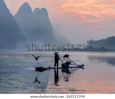 Fisherman stands on traditional bamboo boats at sunrise - The Li River, Xingping, China