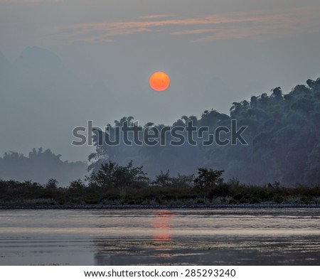 Huge the sun rises above the Li river (on the surface of the Sun is a large group of sunspots) - Xingping, China