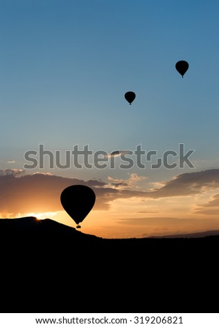 Hot air balloons (atmosphere ballons) flying over mountain landscape in the  Cappadocia at sunset, UNESCO World Heritage Site since 1985) - Turkey
