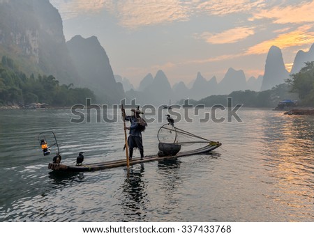 XINGPING, CHINA - OCTOBER 23, 2014: Cormorant fishermen on ancient bamboo boats with lighted lamps and cormorants - The Li River, Xingping, China