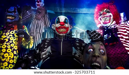 Halloween party scary clowns. Horror clown leader sitting in the electric chair surrounded by terrifying clowns.