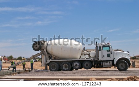 Concrete truck with workers pouring concrete.