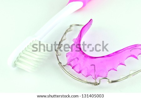 Close up of purple dental braces and toothbrush isolated on whit