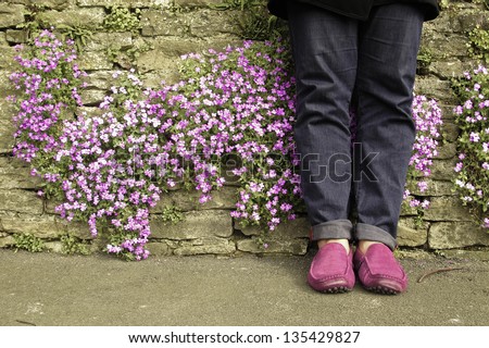 Guy foot lean against the wall with small purple flower