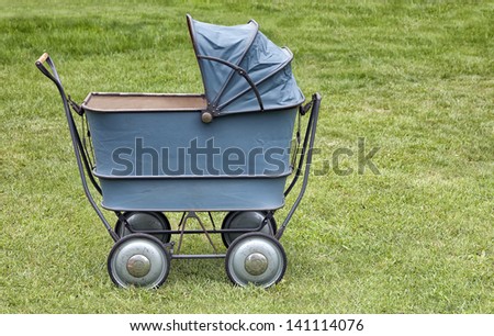 Vintage baby buggy or stroller, outdoors on freshly cut grass.