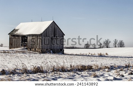 Old wooden barn on plot of open land.  Winter in Wisconsin.
