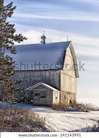 Old wooden barn with field stone foundation in late afternoon light.  Winter in Wisconsin.