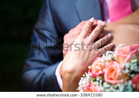 Hands with wedding ring on brides shoulder.