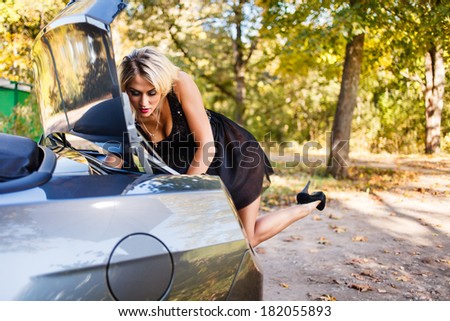 Blond woman searching something in  a car trunk.
