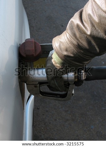 Close-up of a man's hand using a pump to fill car up with fuel.