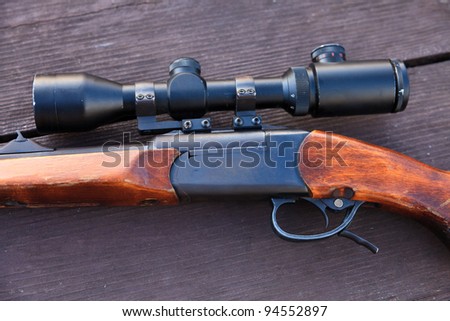 Sniper rifle with optical sight on wooden table.