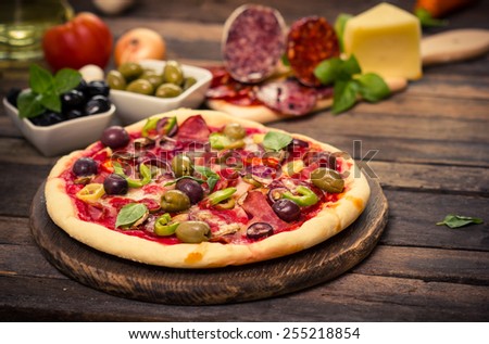 Homemade pizza with ham, cheese, vegetables and pizza ingredients on the table