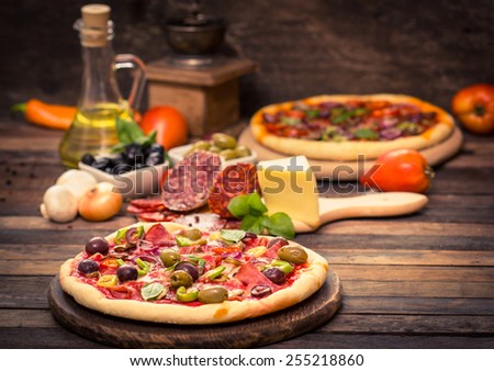 Homemade pizza with ham, cheese, vegetables and pizza ingredients on the table