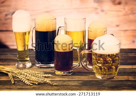 Glasses and mugs with different beers on the wooden table