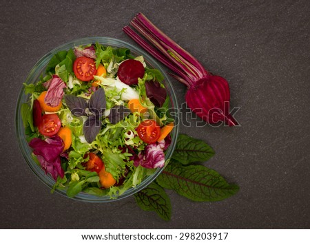 Mixed salad with salad ingredients on the dark background