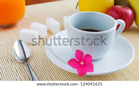 cup of coffee and fruits on a bamboo place mat