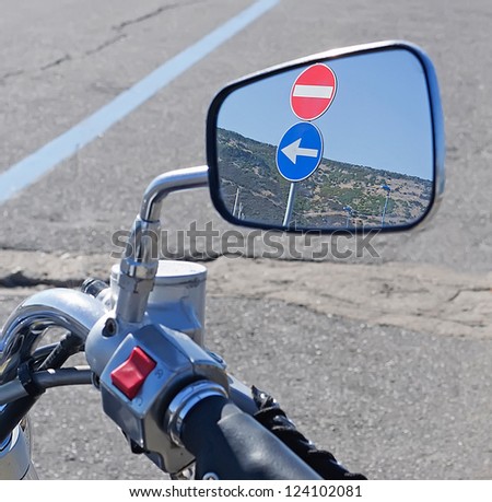 two road signs reflected on a classic bike rear view mirror
