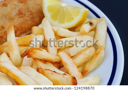 fish and chips with lemon on a white ceramic plate