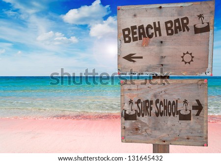 surf school and beach bar sign in a beautiful pink beach under a dramatic sky with sun reflection