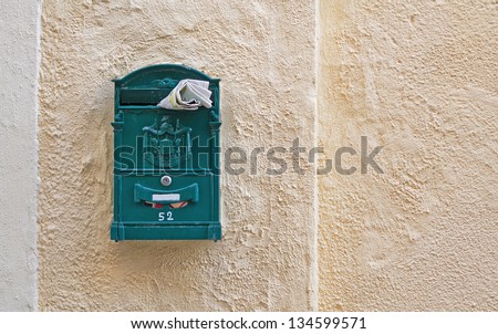 green mail box with a magazine stuck in it