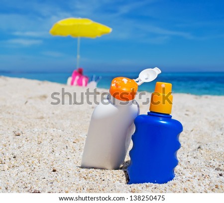 detail of two suntan lotion bottles on the sand
