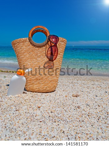 straw bag and suntan lotion under a bright sun
