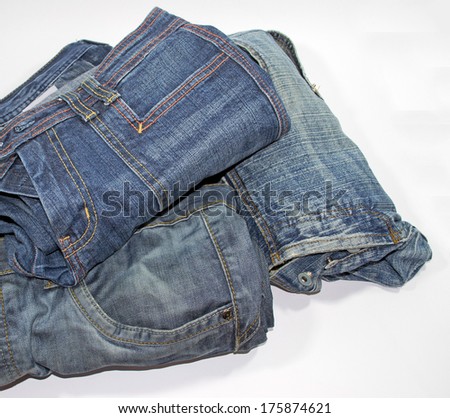 pile of several blue jeans over white background