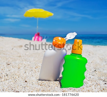 detail of two suntan lotion bottles on the sand