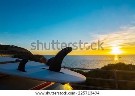 surfboard on a car rooftop at sunset