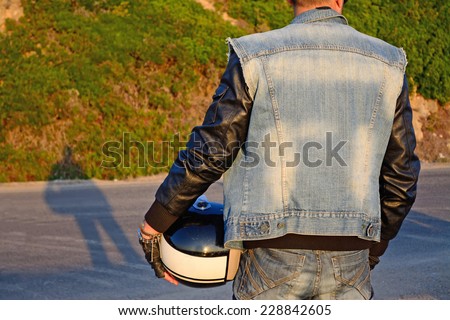 back view of a biker on the edge of the road at sunset