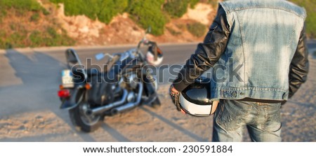 biker and motorcycle on the edge of the road at sunset