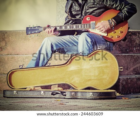guitar player in the street with an open guitar case in vintage tone