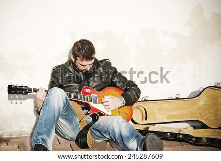 guitar player against the wall with an open guitar case