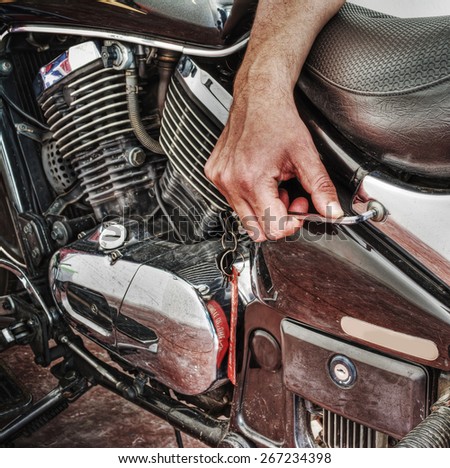 man repairing a classic motorcycle in hdr tone mapping effect